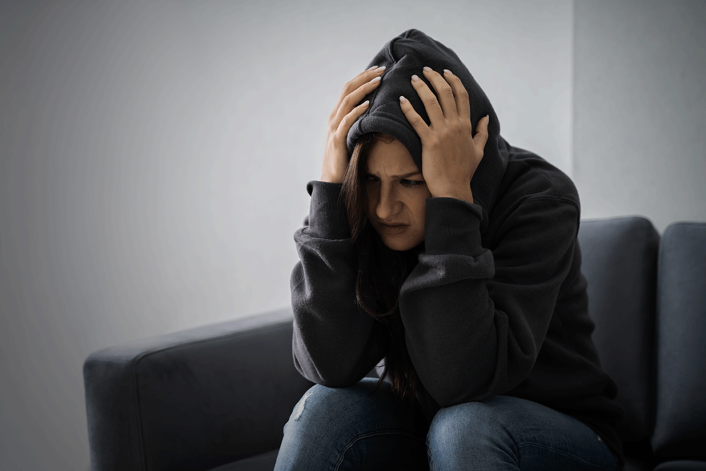 Person sitting on couch with head in hands struggling with meth and adhd