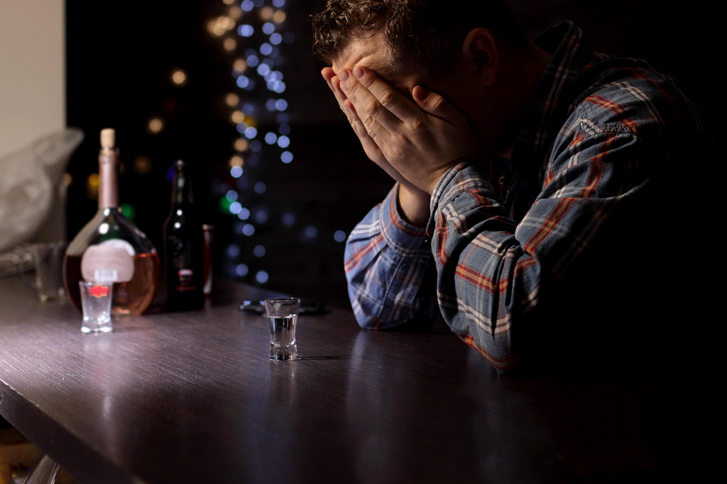 Man at bar with his face in his hands experiencing drinker's remorse