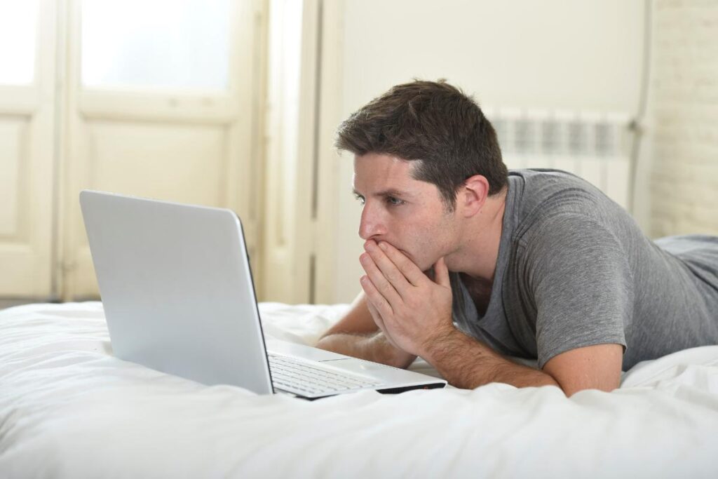 man on computer learning about the symptoms of sex addiction