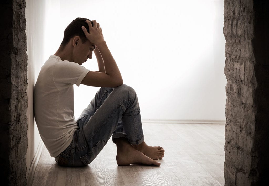 a man sits against a brick wall and considers drug use and abscesses