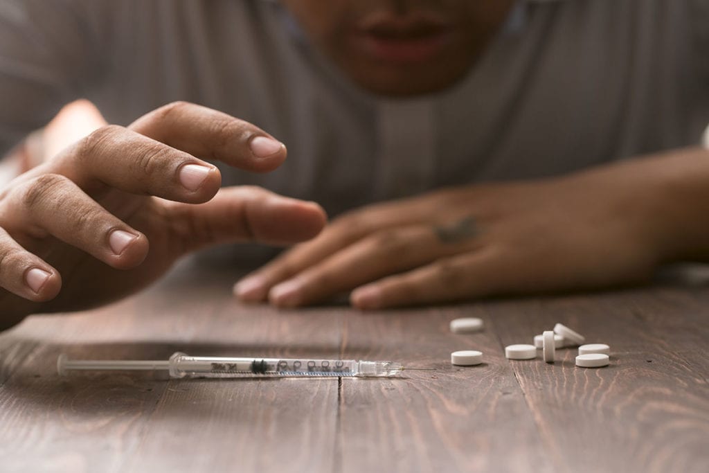 a man reaches for a needle as he considers how today's opioid epidemic mirror the late 19th century morphine addiction phenomenon