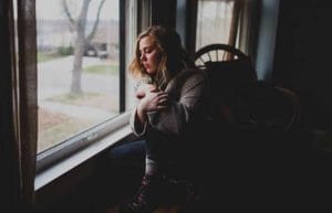 sad woman stands by a window thinking about mood disorder treatment centers