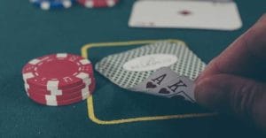 poker chips and hand lifting blackjack cards on a table leading to person looking for gambling addiction treatment centers