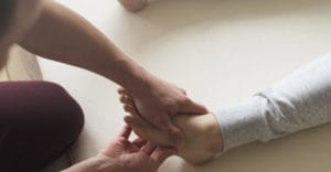 counselor rubs the foot of a patient in a massage therapy program