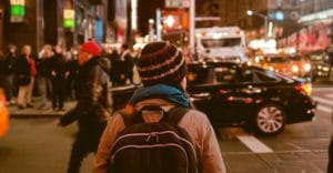 guy with backpack walks through city crosswalk towards relapse prevention counseling