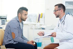 male doctor shows male patient something on clipboard in a behavioral activation therapy program