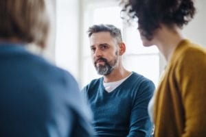 man sits with other patients in group therapy in a dependent personality disorder treatment program