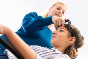 female therapist puts machine on young female patients head at a neurofeedback therapy center