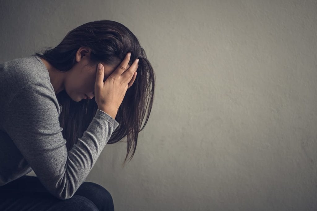 woman sitting with her head in her hands struggling with different types of mental illness