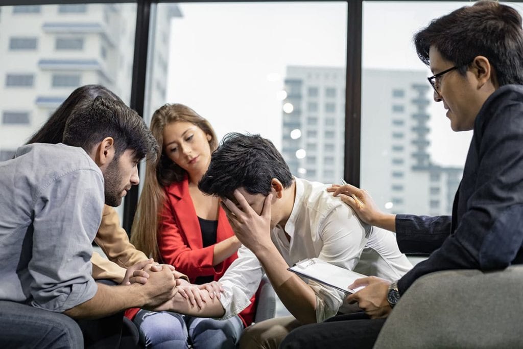 man crying with family supporting him during family therapy activities