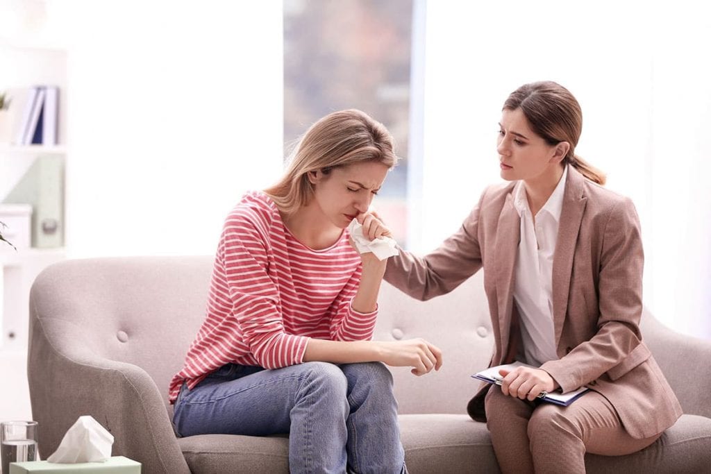 intake specialist sitting with crying wife seeking to learn how to help an alcoholic husband