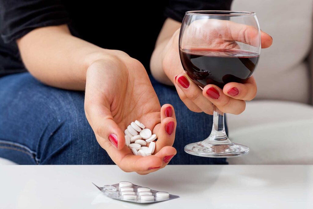 Hands of a person holding Xanax and alcohol