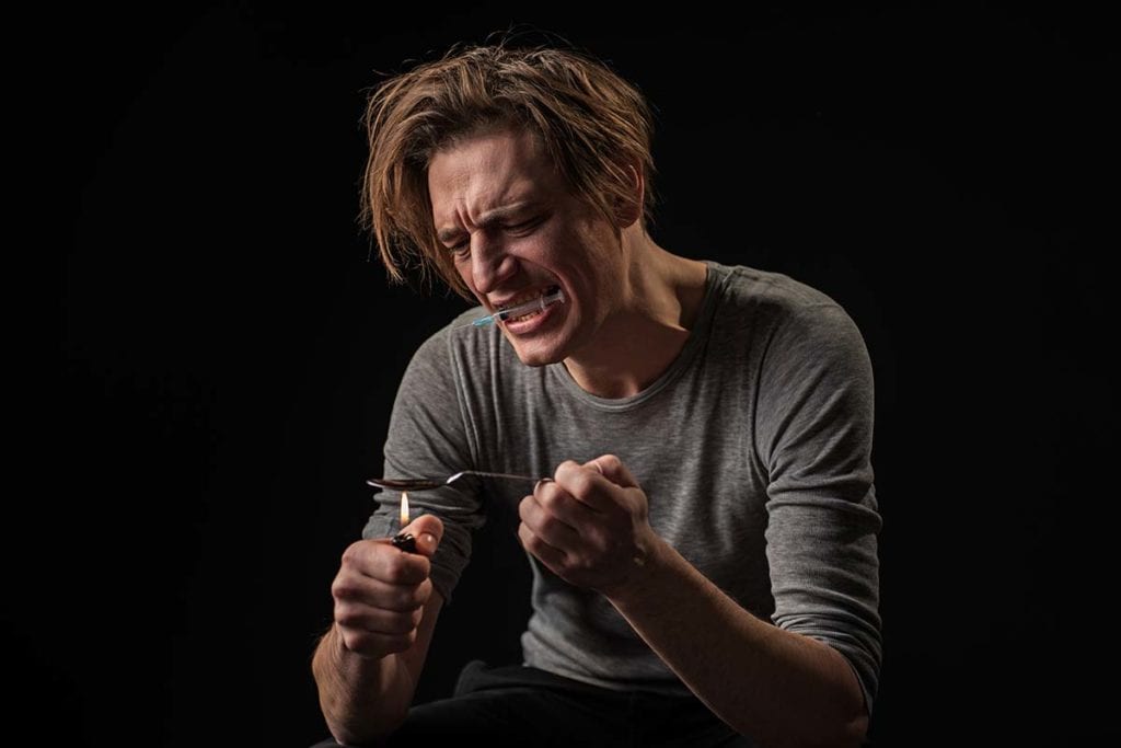 A man gets ready to shoot up with heroin as he wonders how heroin affects the brain