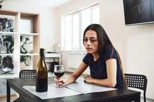 A woman stares at a bottle and considers getting help at a women's alcohol rehab center