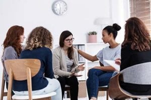 5 women sit in a group at a women's rehab center program