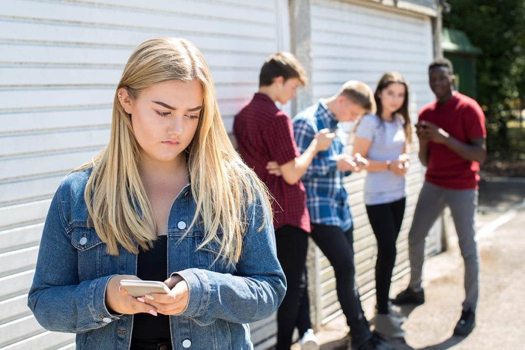 a girl stands apart from her friends as she struggles with depression in high school