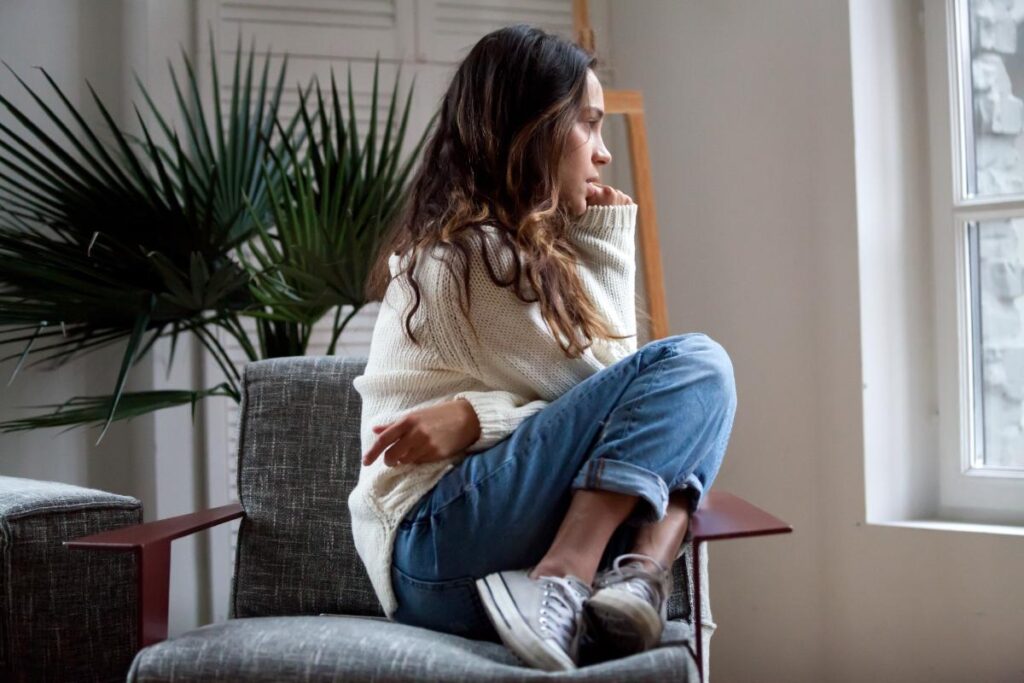 Woman looking out a window contemplating disproven treatments for paranoid schizophrenia