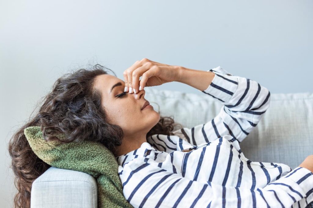 Woman lying down and pinching her nose wondering how long does cocaine stays in your system