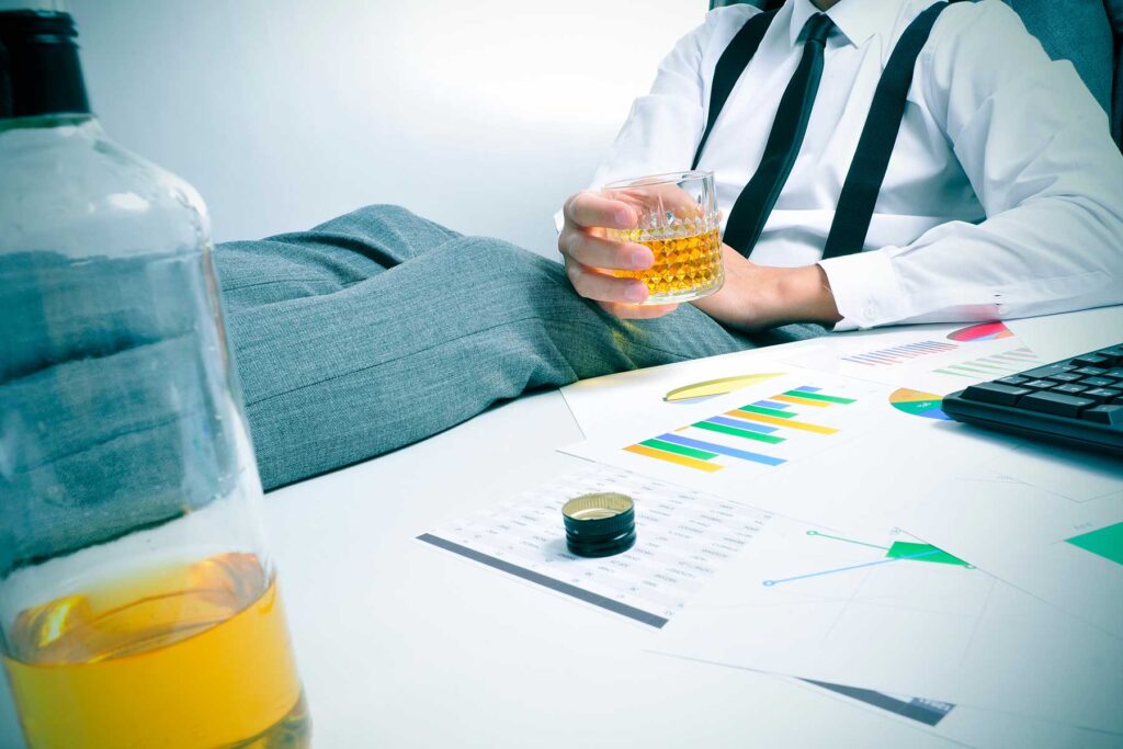 Person behind their work desk, hoping none of their co-workers recognize a functioning alcoholic at the workplace