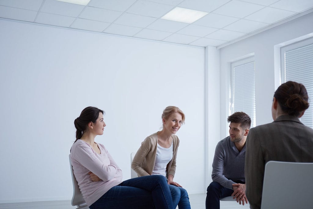 a group of people listen to a description of alcoholic treatment