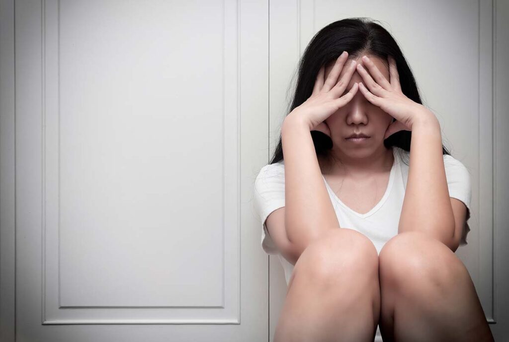 girl with head in hands considers the effects of alcohol on teenagers