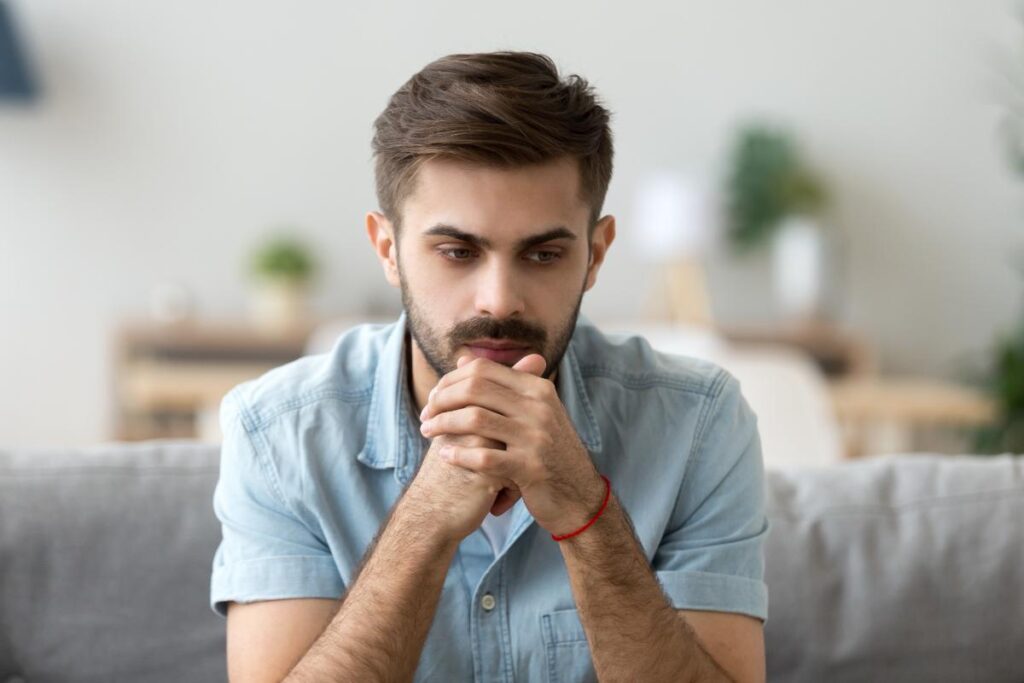 man on couch considering a psychological addiction to drugs