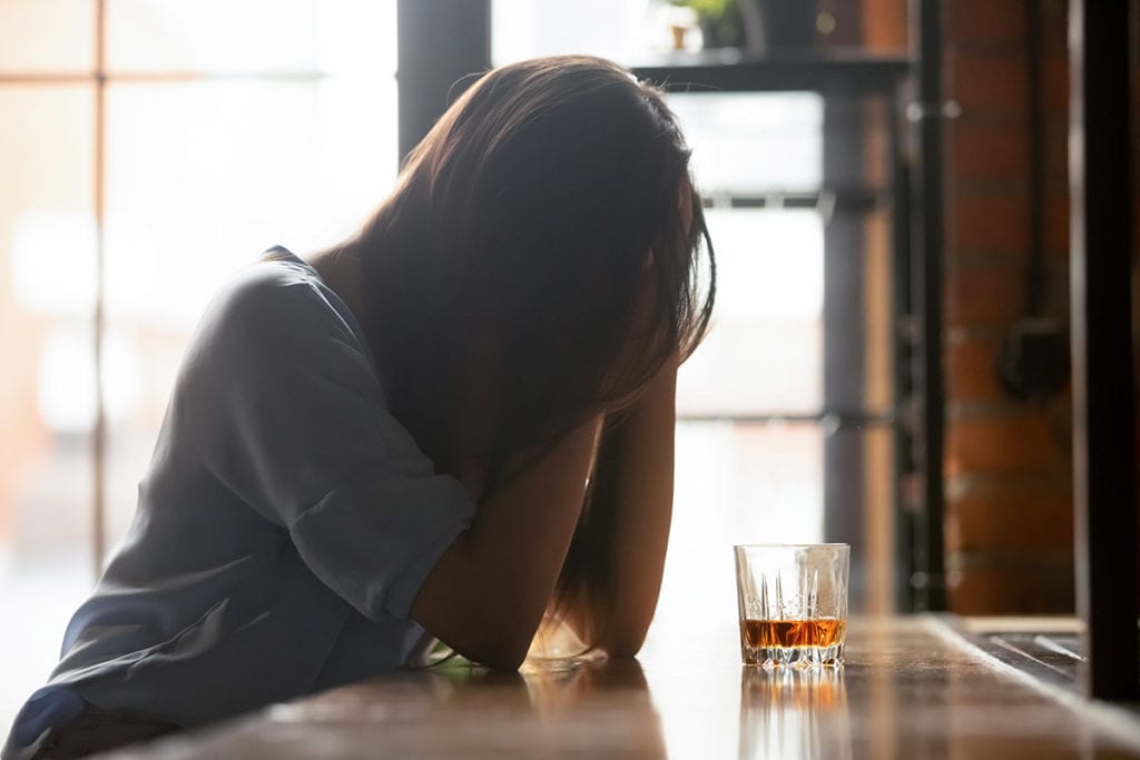 a woman covers her face as she wonders what is alcohol abuse
