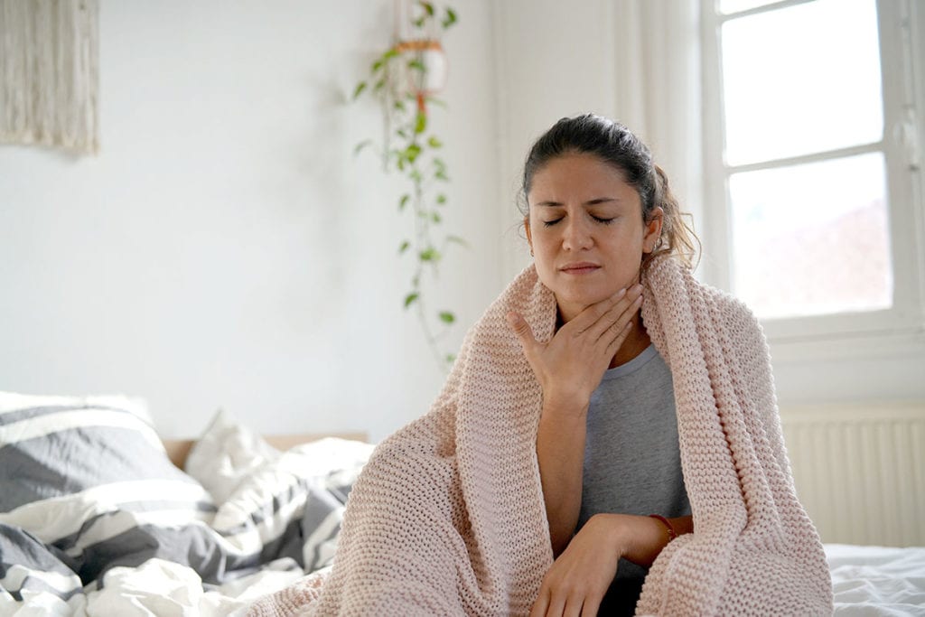 a woman holds her throat as she thinks about her compromised immune system