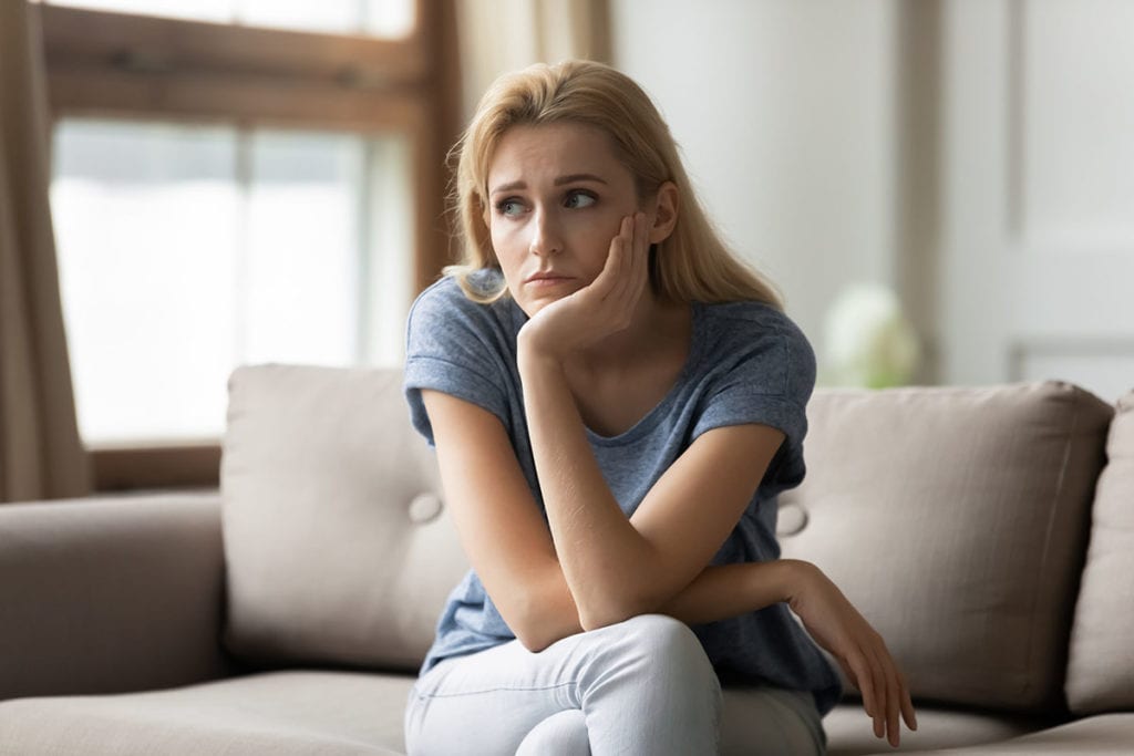 a woman sits with her chin in her hand as as she considers depression treatment in covid-19