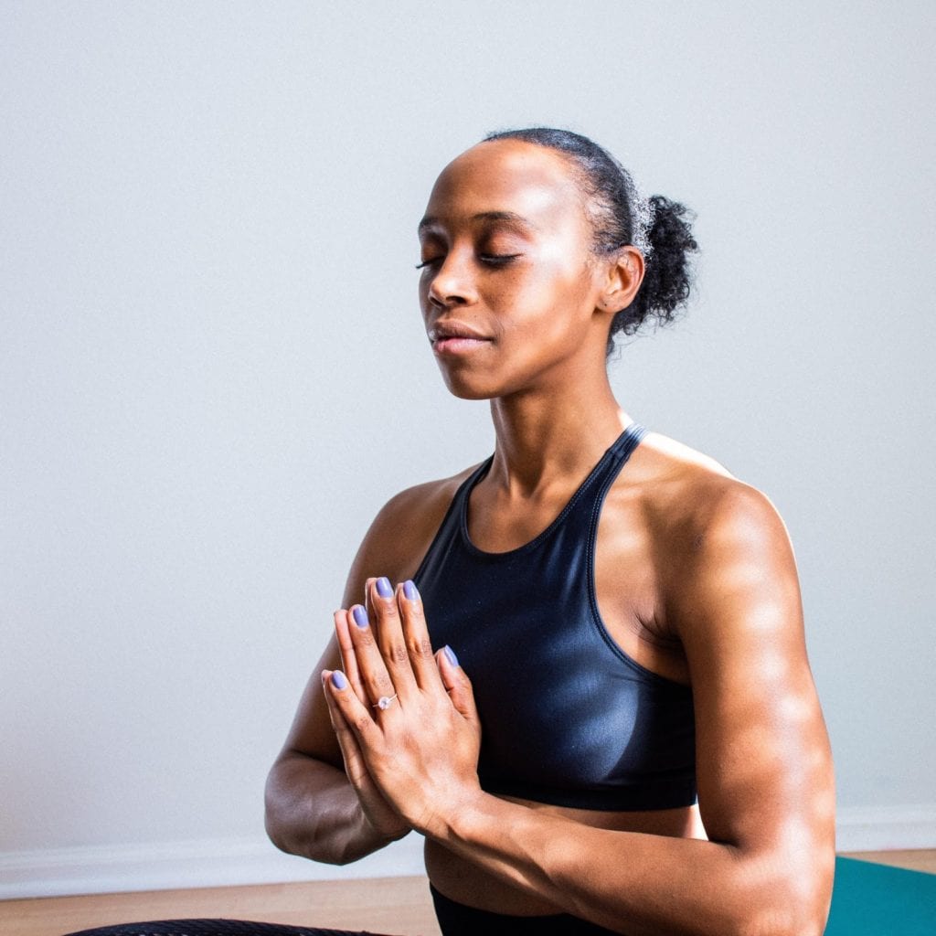 a woman practices yoga as she participates in mental health awareness month