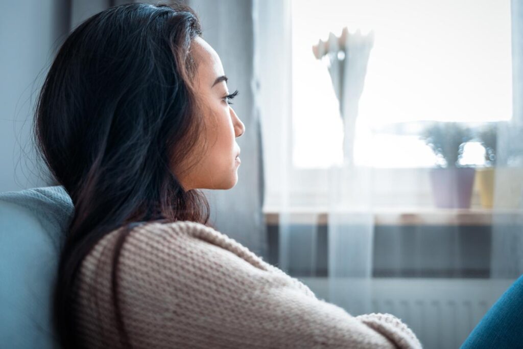 woman looking out of window considers going to rehab for depression