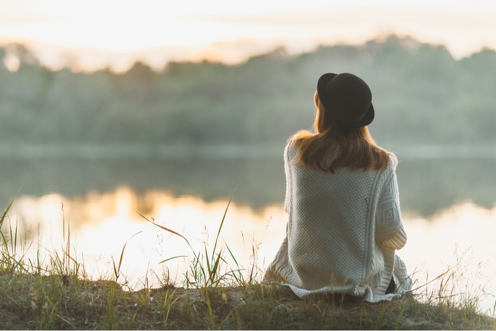 Woman next to lake for mind-body connection in addiction treatment