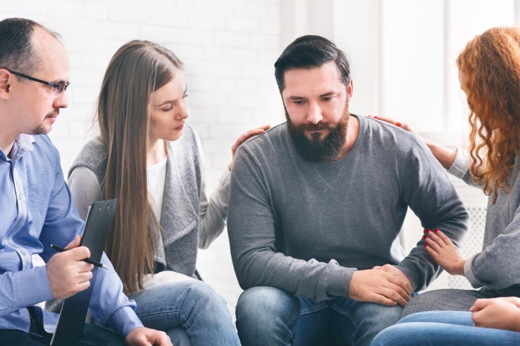 woman comforting man in therapy for trauma and addiction