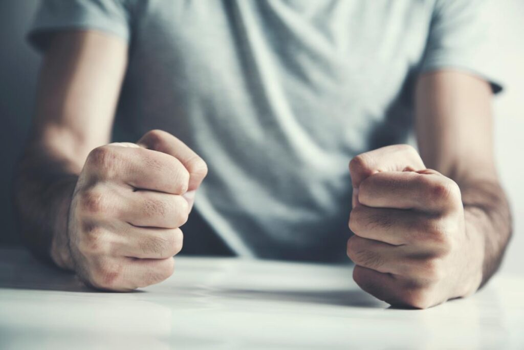 man with fists on table displaying physical signs of anger