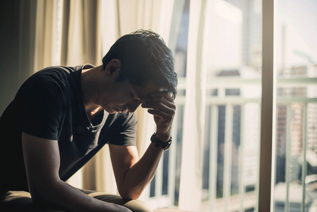 Distressed man sitting in a dark room struggling with PTSD and survival mode