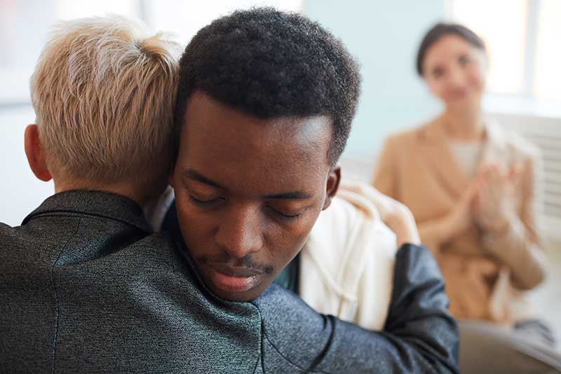 Man hugging member of support group in a heroin addiction treatment center