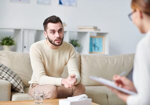 Man with narcissistic personality disorder sits on couch and talks to therapist during treatment