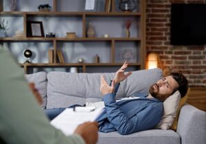 Man lays on couch, talking about his OCD to a clinician at an obsessive-compulsive disorder treatment center